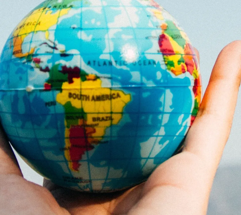 Photographie d'une main détenant une mappemonde